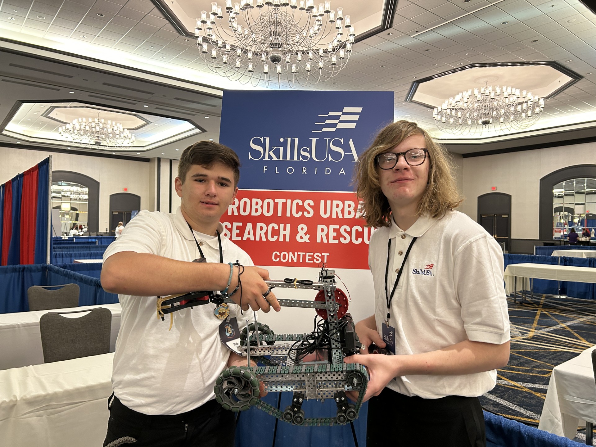 Two men holding a robotDescription automatically generated